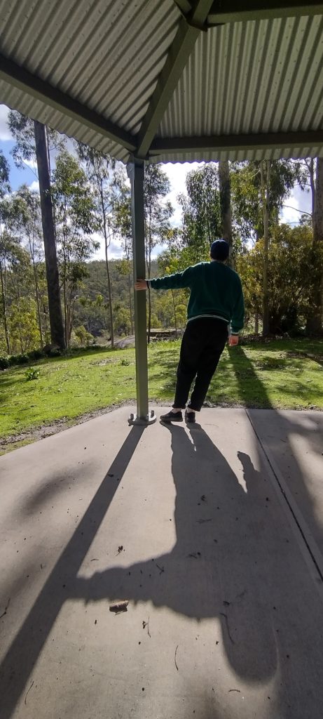 Teenager holding onto a shelter at Mundaring Weir, Western Australia. Her shadow is on the photo as well as some local greenery. 